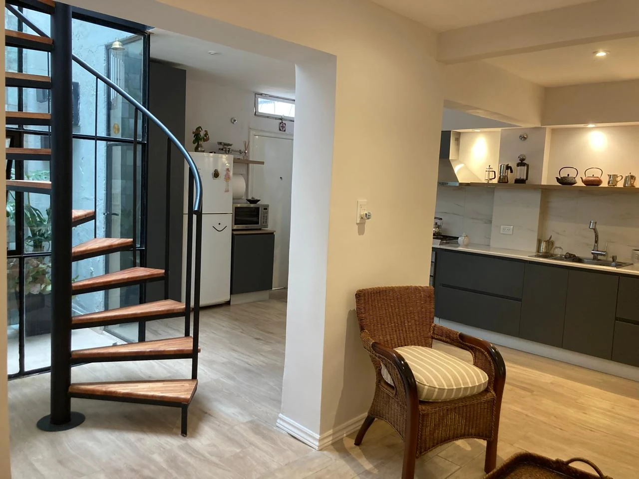 Escalera caracol de hierro y madera junto a una cocina gris